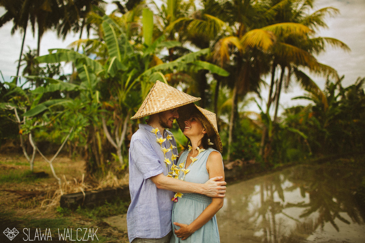 couple posing for ttheir engagemen, maternity photos in between palm trees in Ubud, Bali