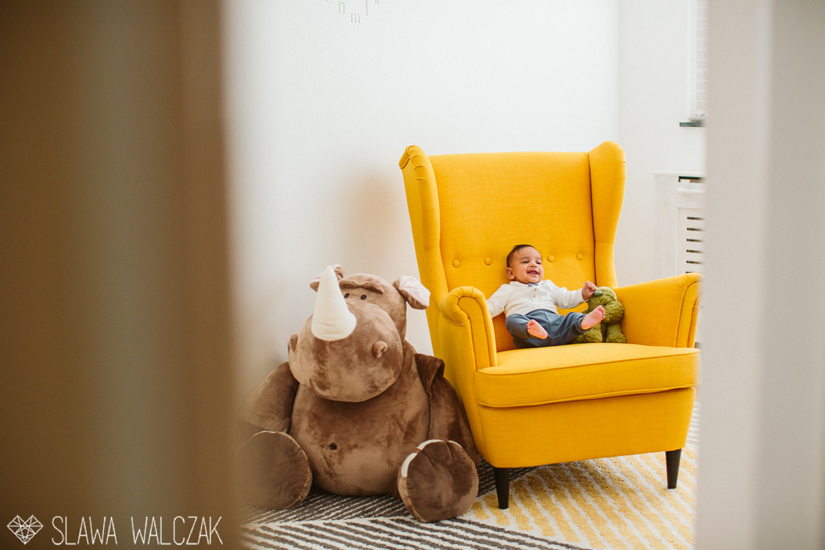 newborn baby giggles in a stylish yellow armchair during a lonfon family photography session
