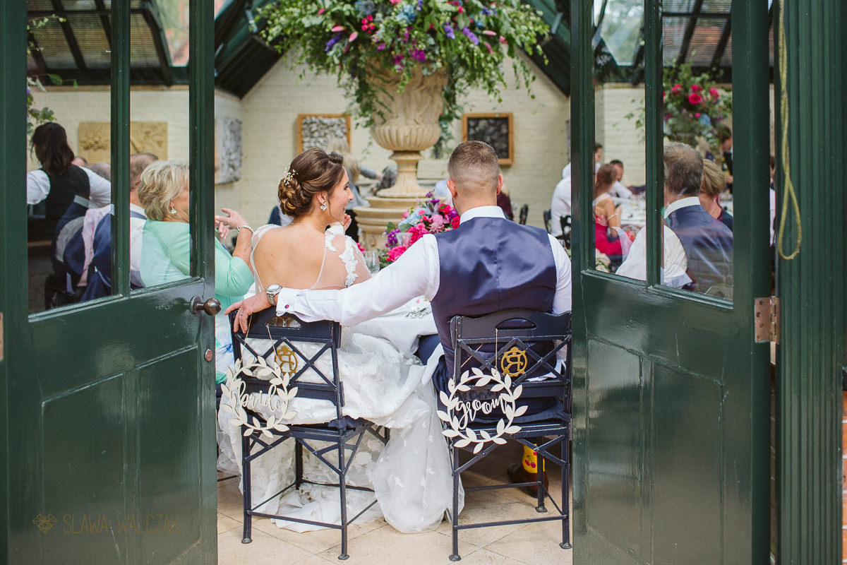 bride and groom aittig at their reception table at the Dairy in Waddesdon