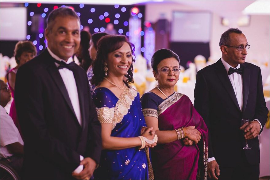 bride and grooms parents welcomong guests at an indian wedding