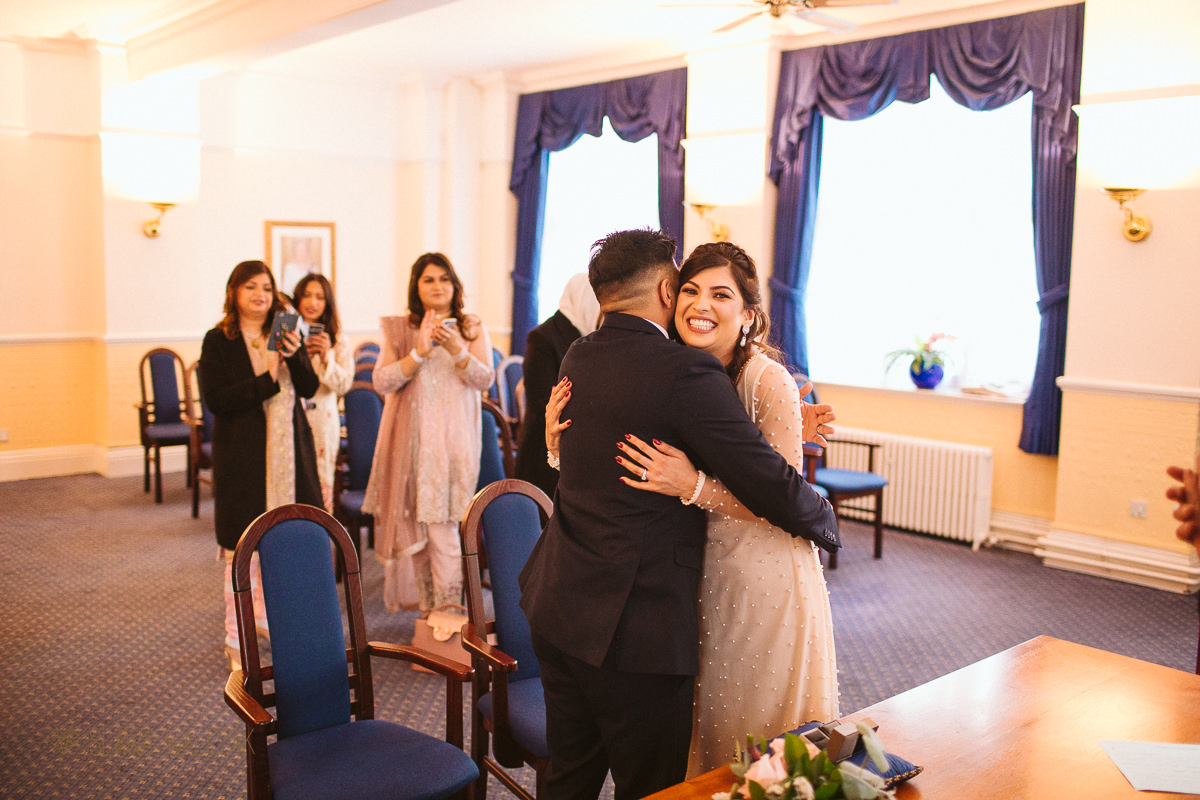 very happy asian bride hugs her husband during a wedding at Ealing Town Hall