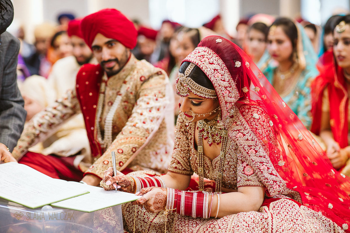 bride signing a registry during his sikh marriage ceremony