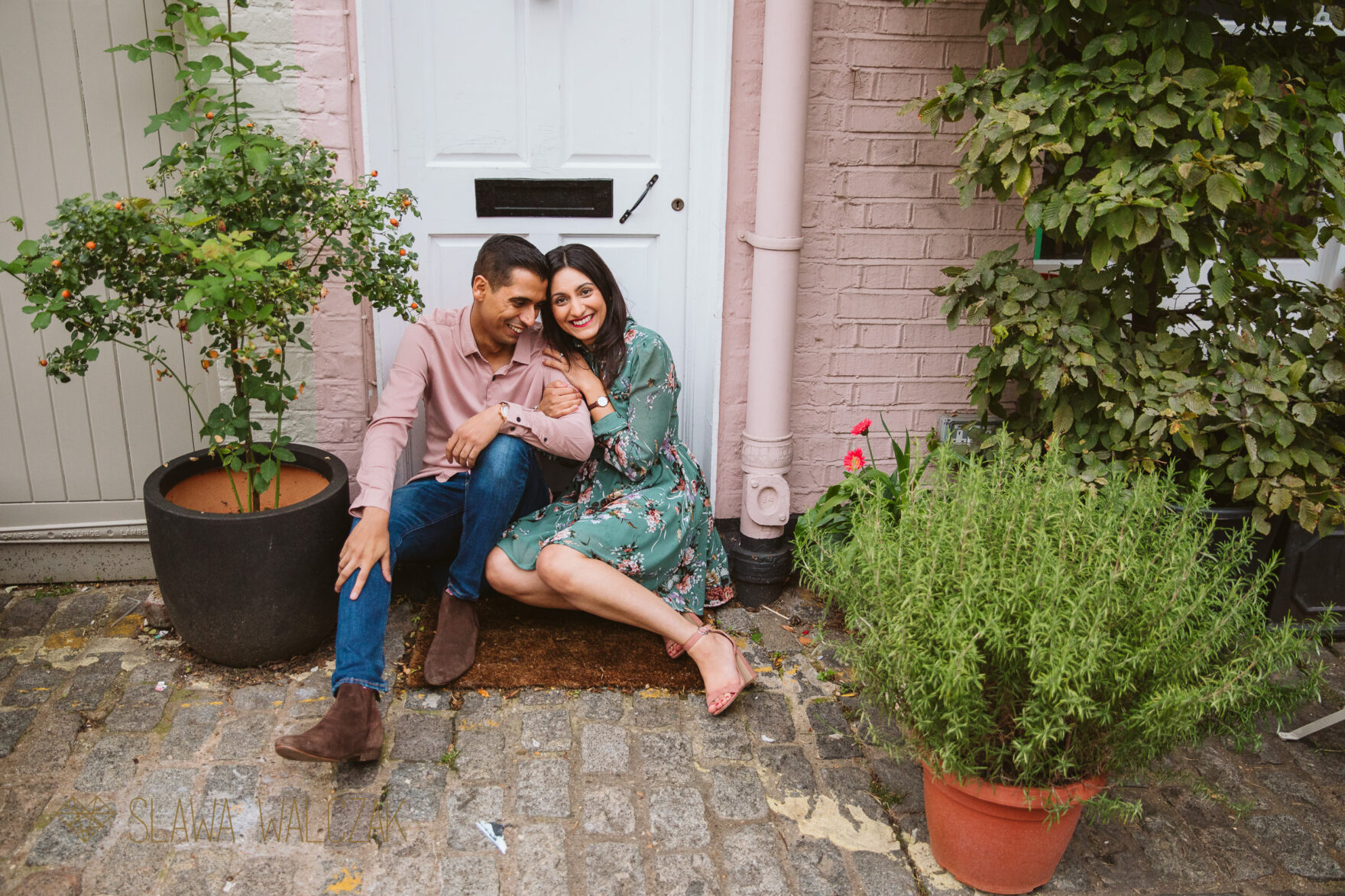 Asian couple posing for photos at a doorstep of a London house