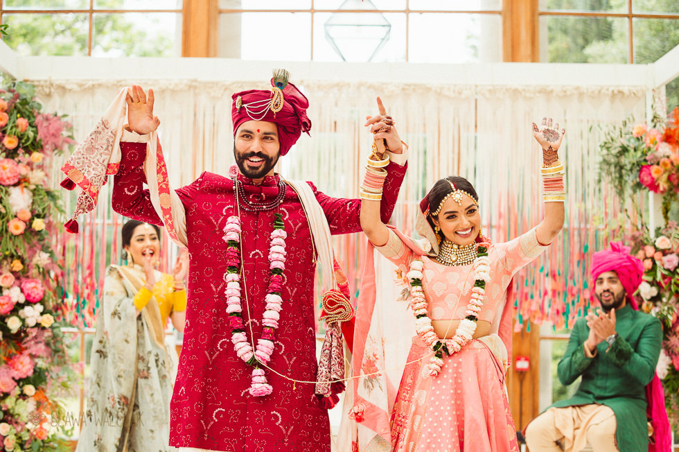 Hindu Bride and Groom Cheering while posing to an Asian London Wedding Photographer at Kew Gardens