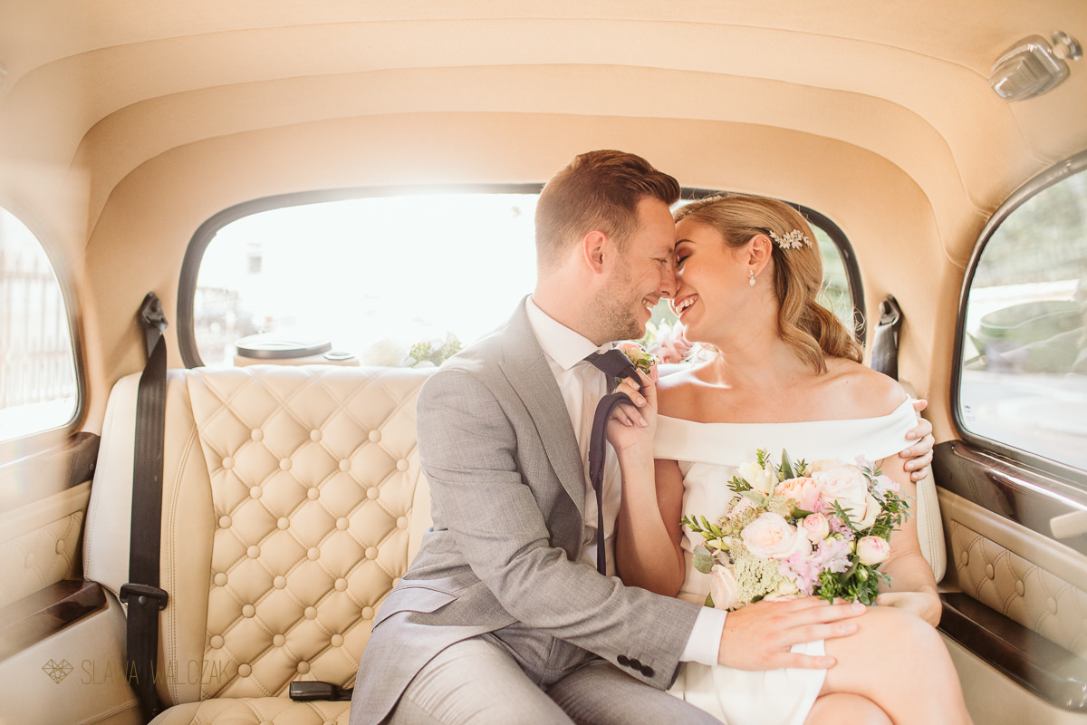 Newlywed couple kissing in the wedding car after their London wedding